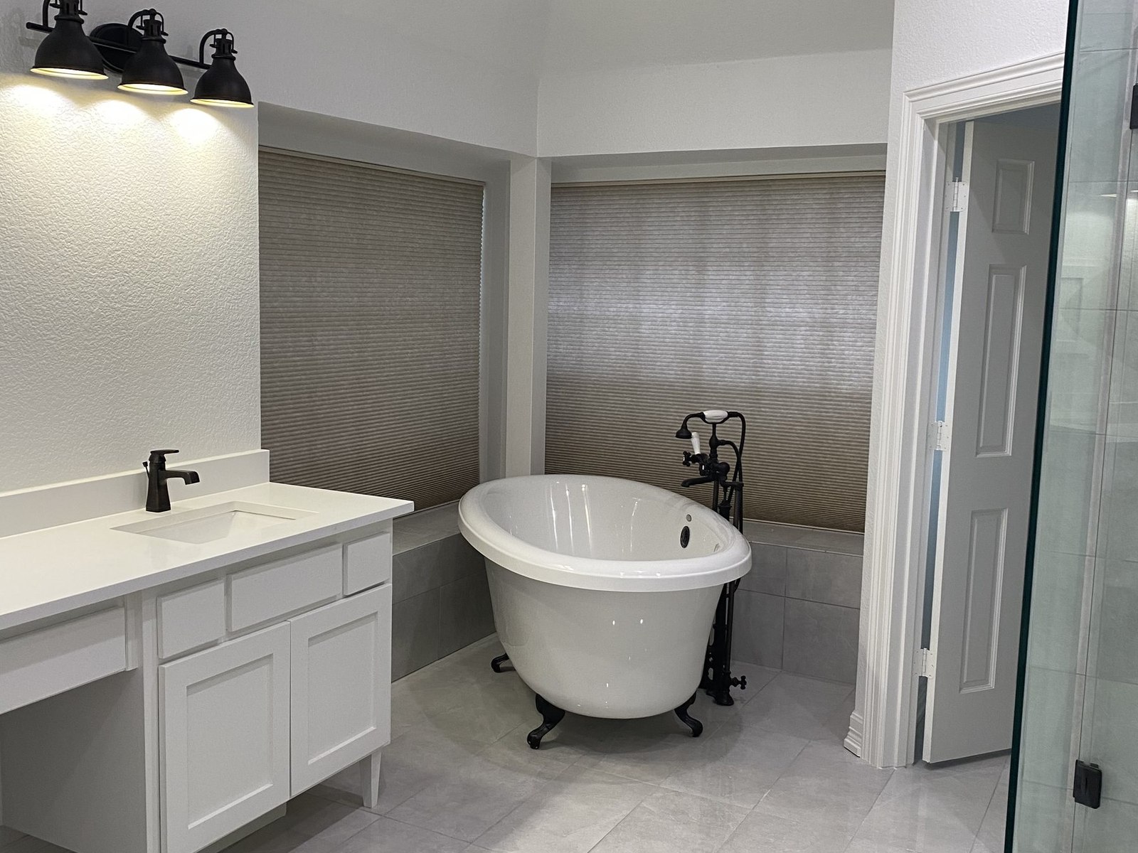 Remodeled primary bathroom with freestanding tub, marble tile and an oak vanity with stone top